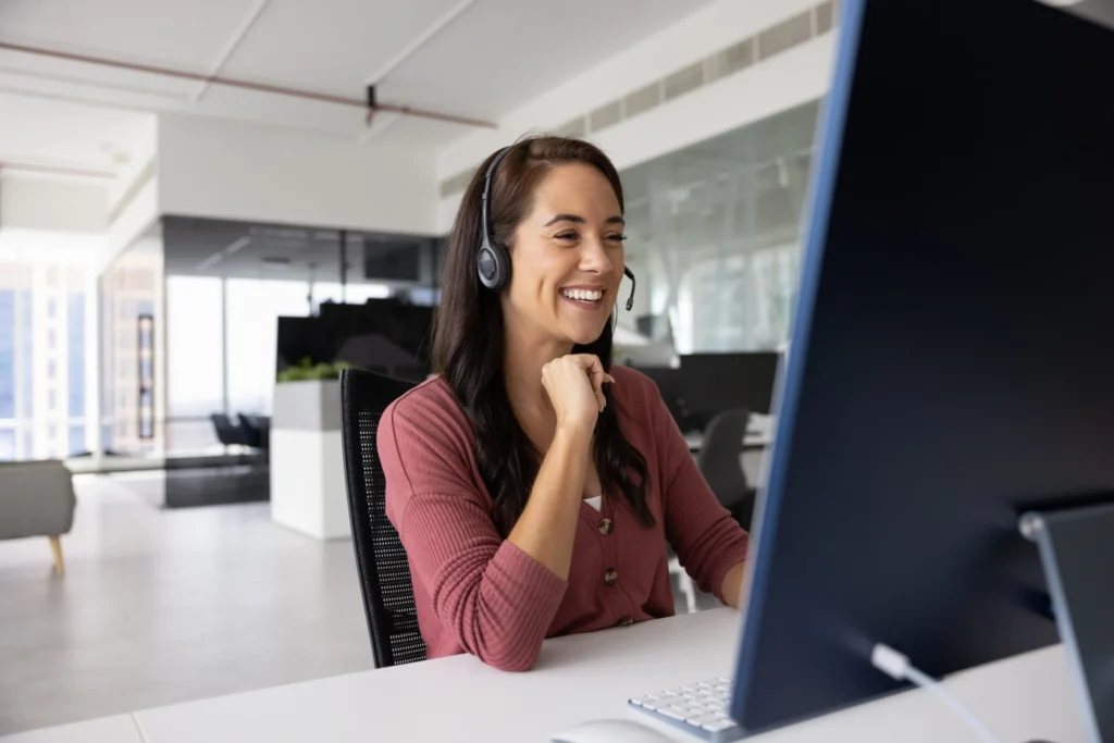 Woman smiling while on computer and using headset